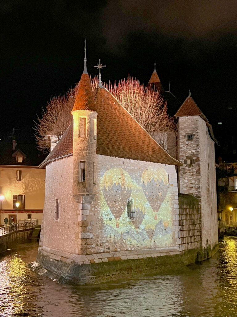 Annecy-christmas-lights-le-palais-de-i'ile Christmas lights projected onto le palais de i'ile in Annecy at night