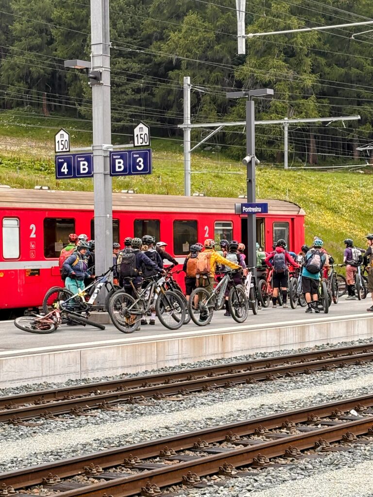 the-bike-train-pontresina tens of people with bikes waiting to get on a red train at Pontresina station, Switzerland