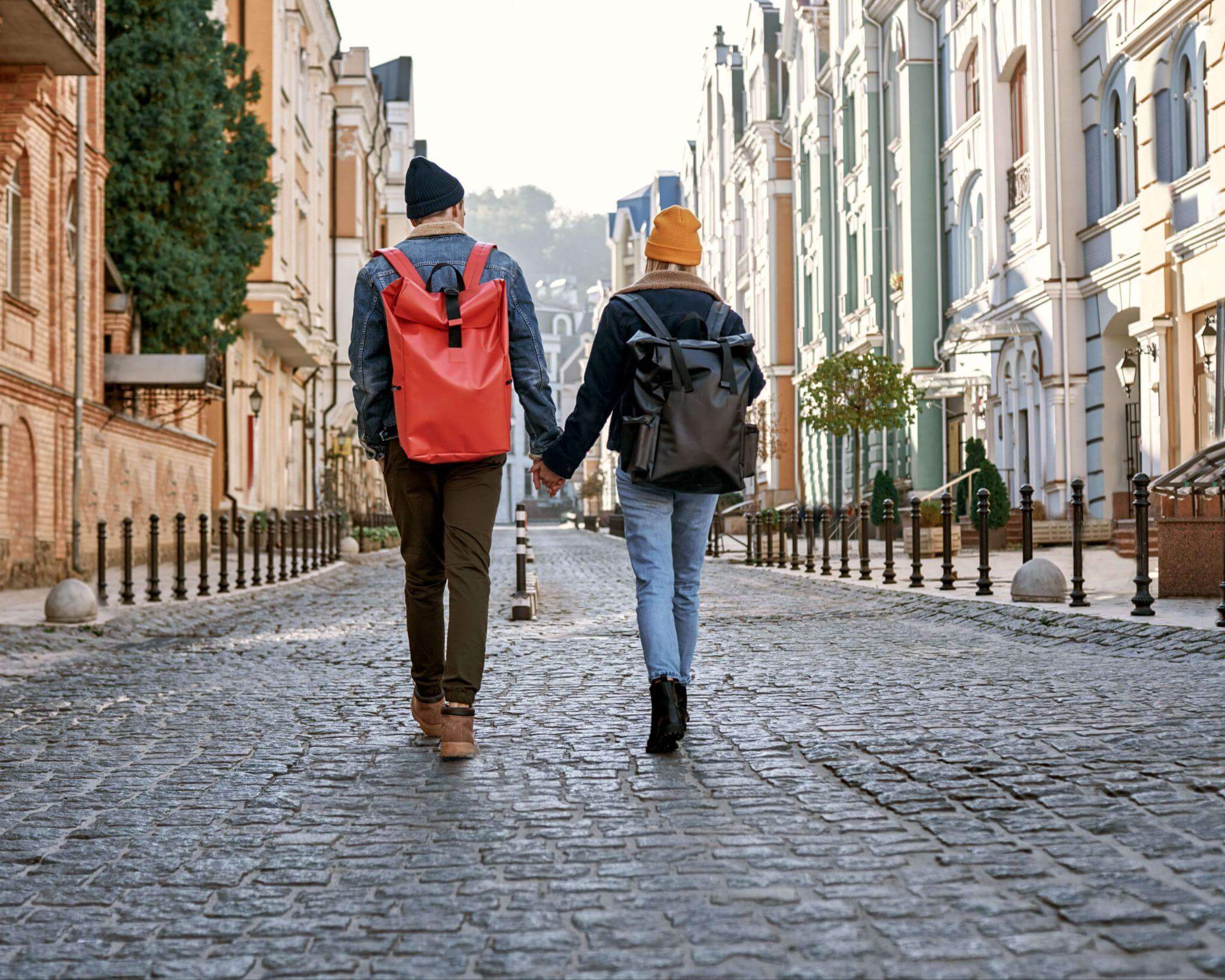 couple walking hand in hand down a cobblestone street in exploring the sites by foot