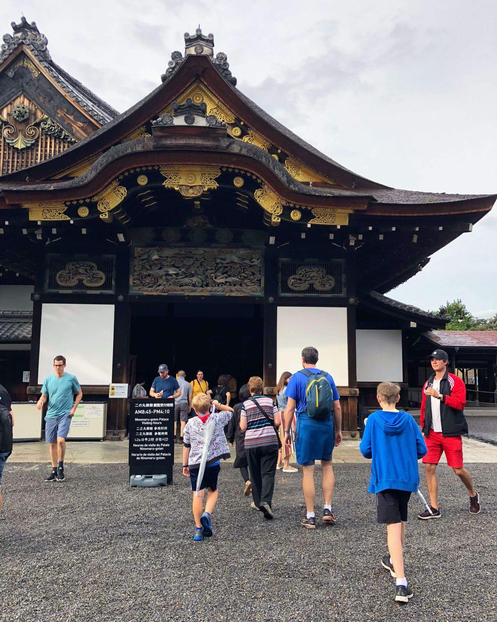 Family entering a shrine in Tokyo city, the shrine is old, wooden with ornate gold leaf decoration