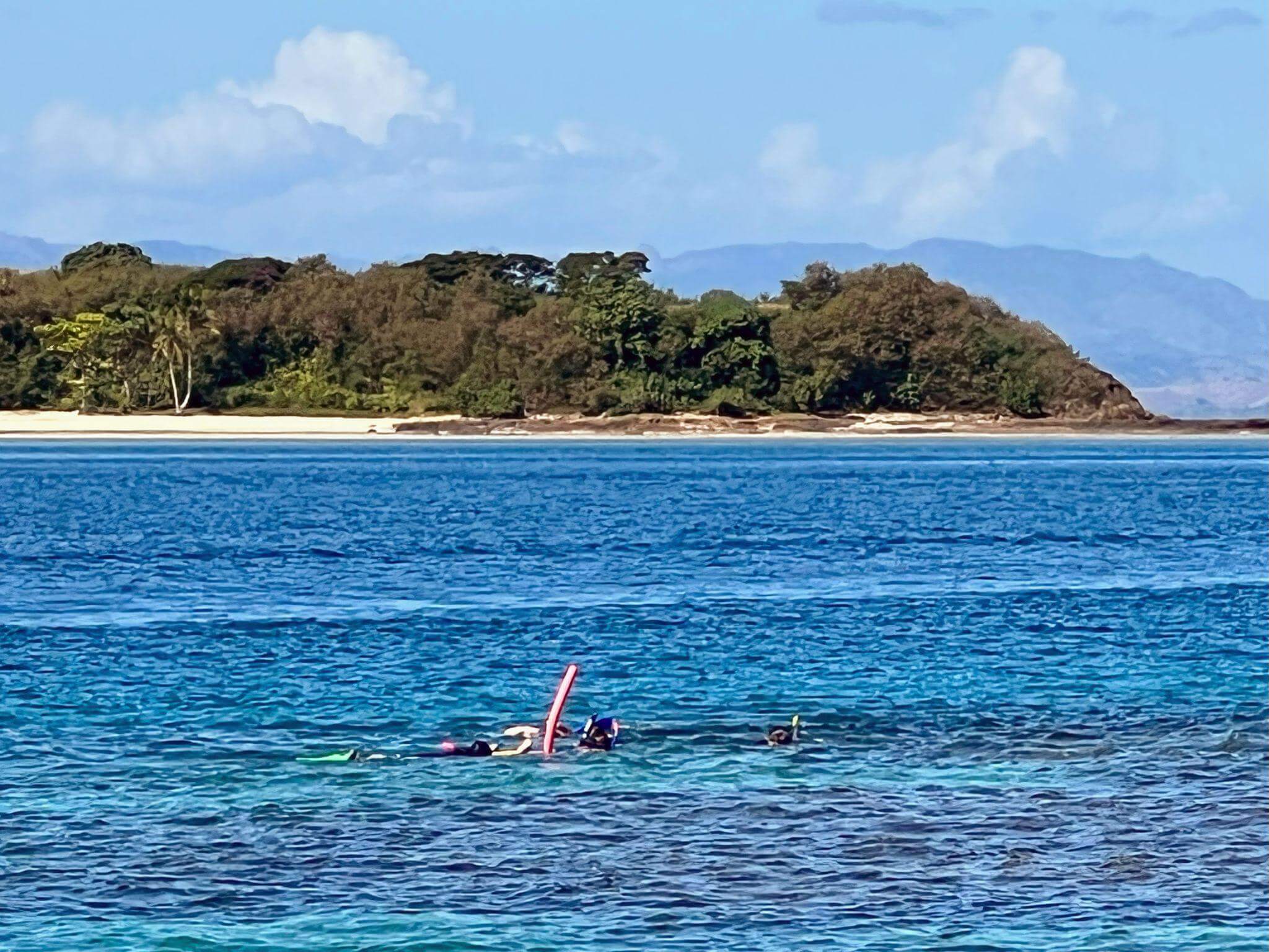 group of people snorkelling in fiji with vibrant blue warm water and tropical islands in the background
