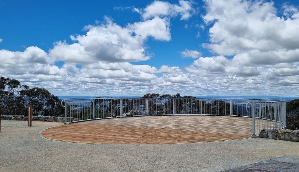Spectacular daytime panoramic view from Mount Canobolas Summit Lookout showing the vast central west NSW landscape with rolling hills, farmland, and distant mountains under blue skies