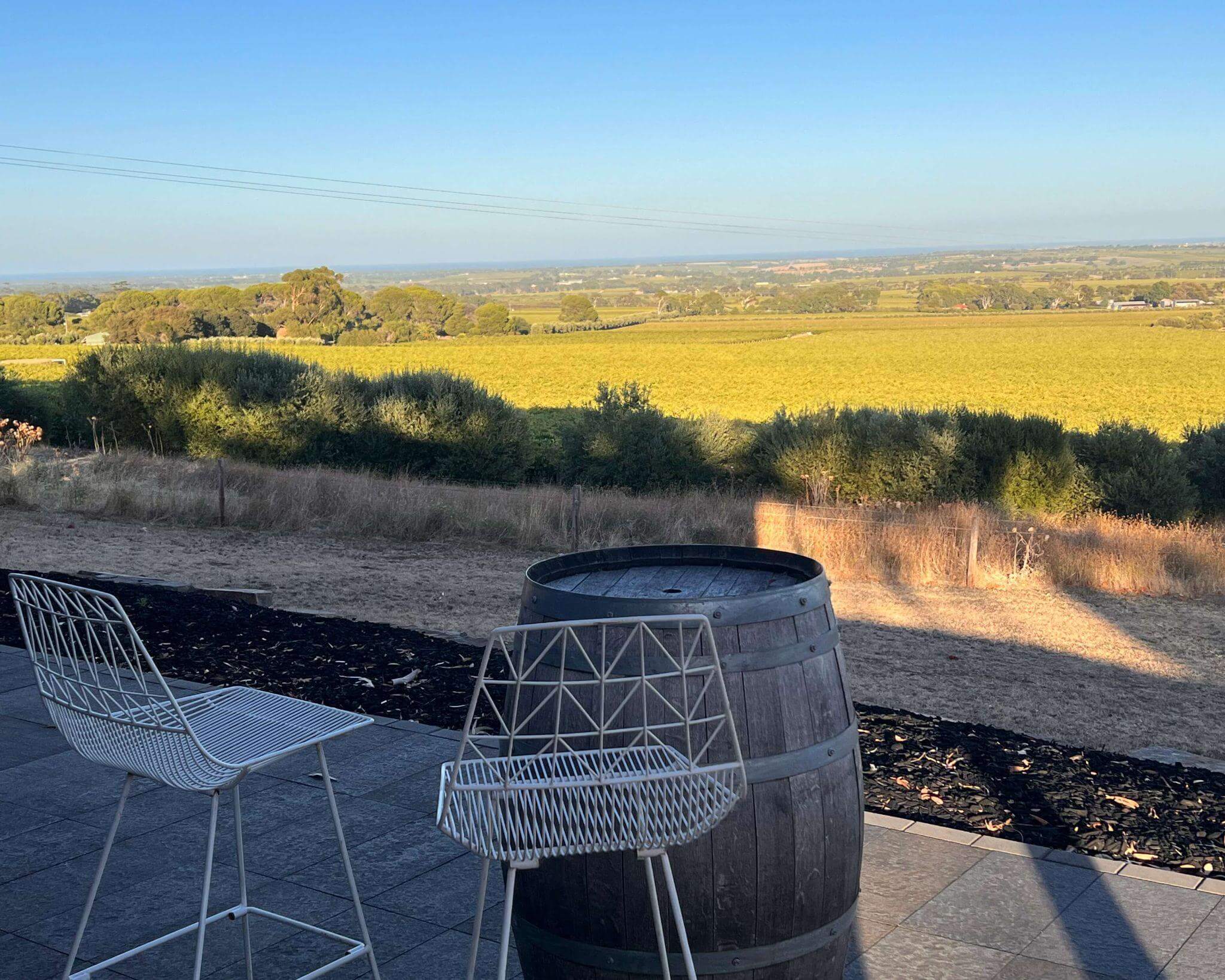 two high shares and wine barrel table on the outside deck of boutique accommodation overlooking wineries and the ocean in mcclaren vale south australia
