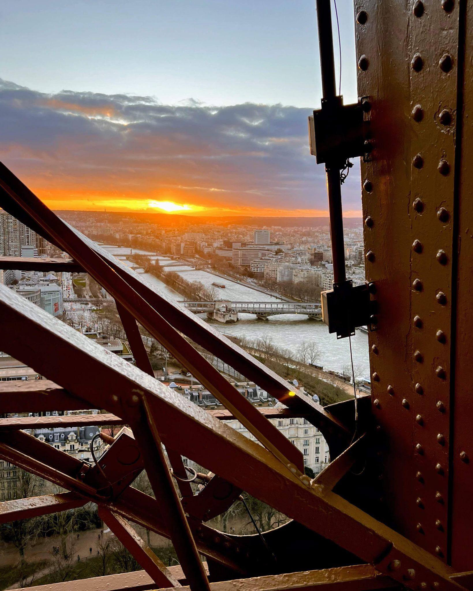 view from the middle viewing platform on the eiffel tower at sunset with a view down the Seine river and the beautiful old buildings of paris