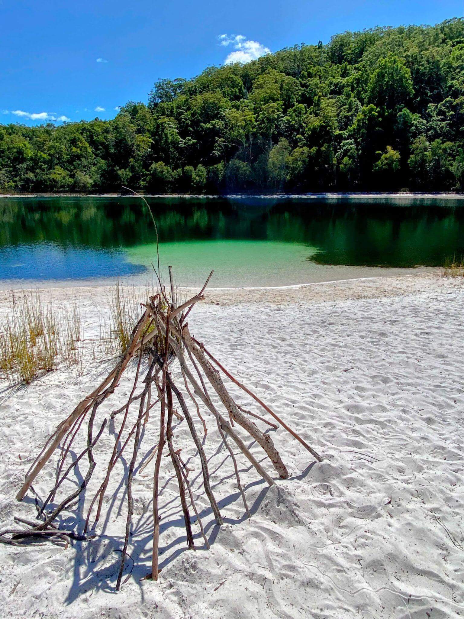 Crystal clear lake with white sand beach and green forest perfect for multi-day hiking rest stop and water access