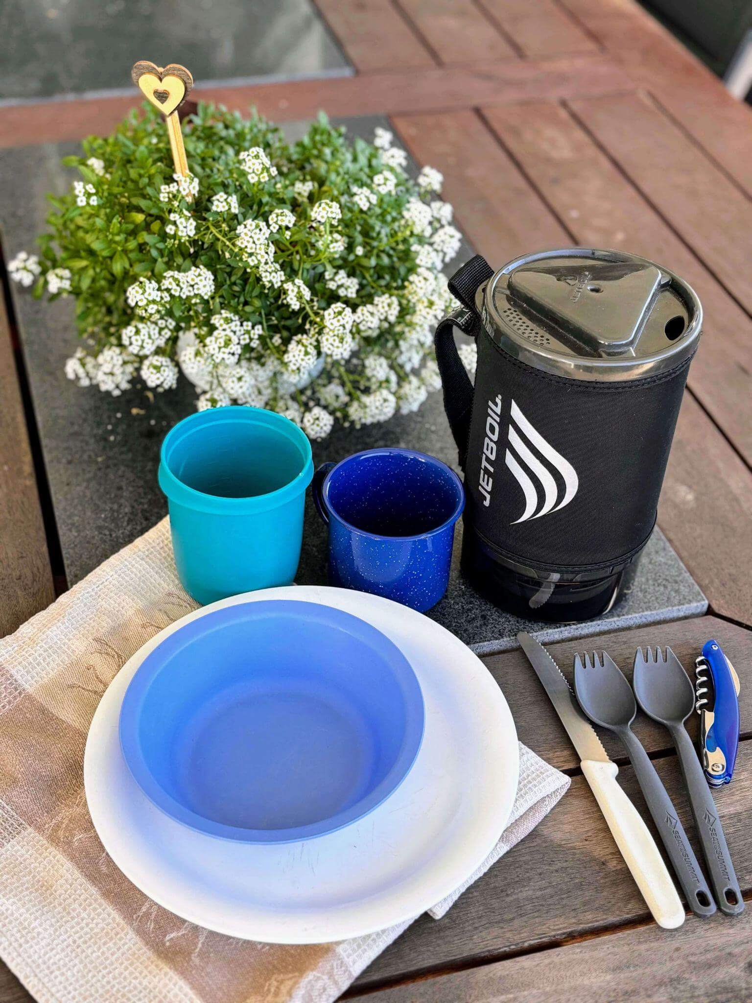 Lightweight multi-day hiking cookware setup featuring Jetboil stove, camping cups, plates and sporks - essential gear for trail meal preparation and outdoor cooking
