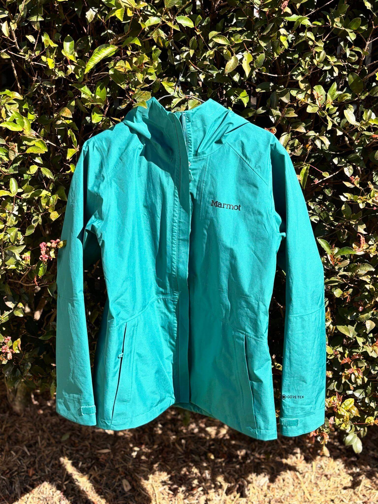 Marmot Gore-Tex waterproof hiking jacket hanging against foliage - essential gear for hut to hut hiking packing list